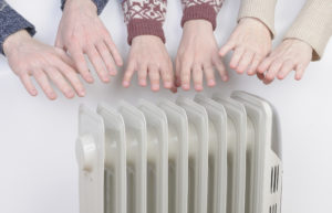 Family warming up hands over electric heater