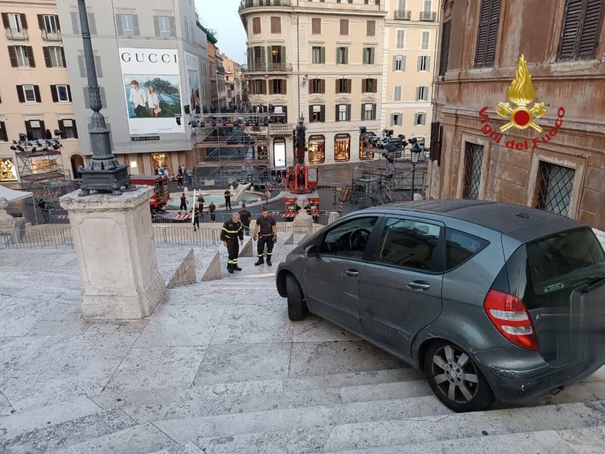 Con l'auto percorre la scalinata di Piazza di Spagna a Roma - 